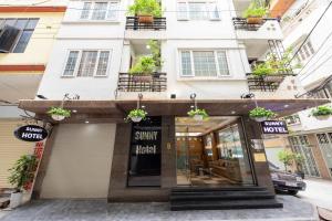 a store front of a white building with potted plants at Sunny Hotel in Hanoi