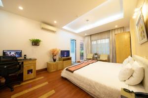 een slaapkamer met een bed, een bureau en een televisie bij Sunny Hotel in Hanoi