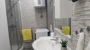 a bathroom with a sink and a mirror and yellow towels at Anđela Home - Krka waterfalls in Lozovac