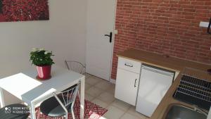 cocina con encimera blanca y pared de ladrillo en Appartement tout confort au calme avec jacuzzi, en Mouguerre