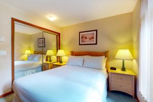 1 dormitorio con 2 camas, 2 lámparas y espejo en Lagoons at Stoney Creek, en Whistler