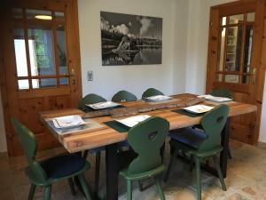 ein großer Holztisch mit grünen Stühlen um ihn herum in der Unterkunft Naturforsthaus Gartenblick für tier- und naturverbundene Menschen in Preitenegg
