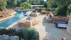 a pool with people laying on couches in the water at Villa Delle Palme in Trepuzzi