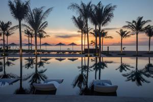 a swimming pool with palm trees and a sunset at Alma Resort Cam Ranh in Cam Ranh +53 photos