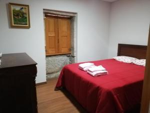 a bedroom with a red bed with two towels on it at Casa das Bouças in Viana do Castelo