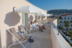 two people sitting in chairs on the balcony of a building at Cristal Hôtel & Spa in Cannes