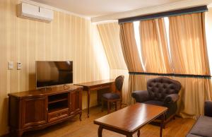 a hotel room with a television and a table and chairs at Chizay. Мала Гора in Berehove