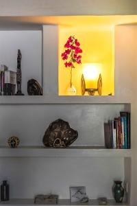 a shelf with a vase with flowers and a lamp at Jardim dos Aloés, Unique B&B - Casa de Charme in Ilha de Moçambique