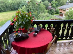 a table with a red table cloth on a balcony at Sallanches 3101 Route de Nant Cruy immeuble le Grand R in Sallanches