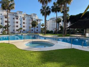 a swimming pool in a park with palm trees and buildings at Mi Capricho Apartment with Sea Views and Gardens in La Cala de Mijas