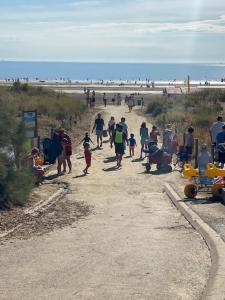 eine Gruppe von Menschen, die eine unbefestigte Straße in Strandnähe entlang gehen in der Unterkunft La Villa Rose-Marie in Saint-Brevin-les-Pins