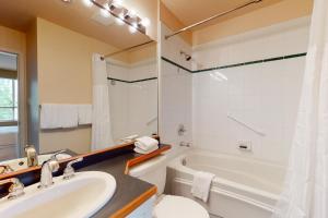 a bathroom with a sink and a tub and a toilet at Town Plaza Suites in Whistler