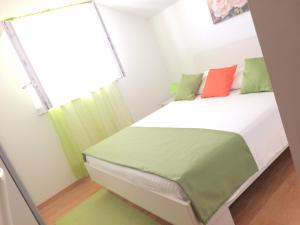 Dormitorio pequeño con cama con almohadas verdes y naranjas en Apartments Lea, en Cavtat