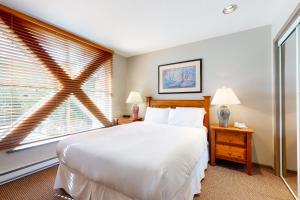 ein Schlafzimmer mit einem großen weißen Bett und einem Fenster in der Unterkunft Town Plaza Suites in Whistler