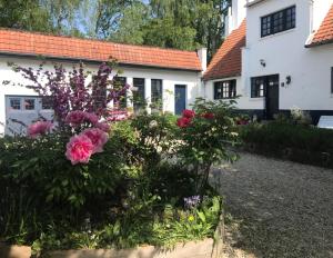 un jardin en face d'une maison blanche ornée de fleurs dans l'établissement Bed and Breakfast Ros & Marc, à Wezembeek-Oppem