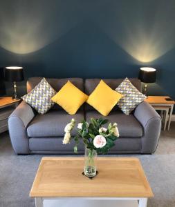 un sofá con almohadas y un jarrón de flores sobre una mesa en Queen Street Apartments, en Enniskillen