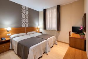 バルセロナにあるカタルーニャのベッド1台、薄型テレビが備わるホテルルームです。