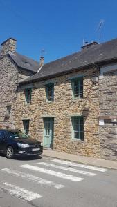 a stone building with a car parked in front of it at Le Gîte de Caradoc in Paimpont