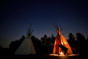 two tents with a fire in a field at night at Fort Wapiti in Zalasowa +32 photos