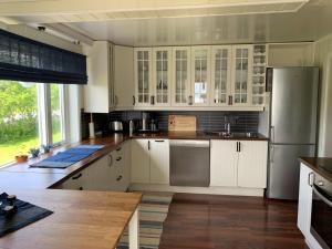 cocina con armarios blancos y nevera de acero inoxidable en House in central Finnsnes en Finnsnes