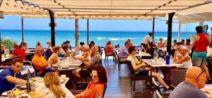 eine Gruppe von Menschen isst in einem Restaurant am Strand in der Unterkunft Mi Capricho, Luxury Apartment in Mijas Costa