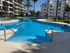 a large swimming pool with blue water and palm trees at Mi Capricho, Luxury Apartment in Mijas Costa +38 photos