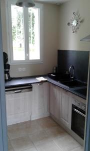 a kitchen with white cabinets and a sink and a window at Le Lutice in Aunay-sur-Odon