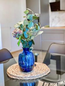 eine blaue Vase mit Blumen auf einem Glastisch in der Unterkunft Seaview Apt Koper 1 in Koper