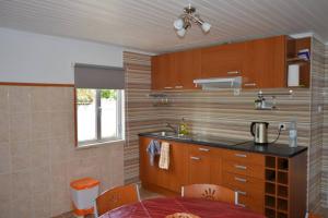 a kitchen with wooden cabinets and a table and a sink at Casa 4 Estaçoes in Batalha