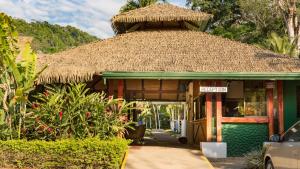 a building with a thatched roof with a car parked outside at Hotel Villas Rio Mar in Dominical