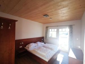 a bedroom with a bed with a wooden ceiling and a window at Stoffis Hütten in Tauplitz