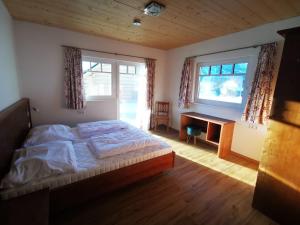 a bedroom with a bed and a desk and two windows at Stoffis Hütten in Tauplitz