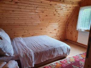 a bedroom with a bed in a wooden wall at Casa Dor de Ea in Dâmbovicioara