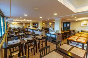 a restaurant with wooden tables and chairs in a room at A Furninha Hotel in Torres