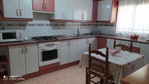 a kitchen with red and white cabinets and a table at Casa Rural El Cerrete 2 in Riópar