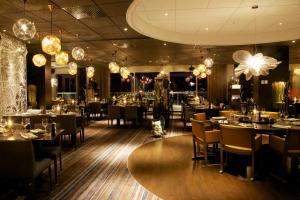 una sala da pranzo con tavoli, sedie e lampadari di Clarion Hotel Sense a Luleå