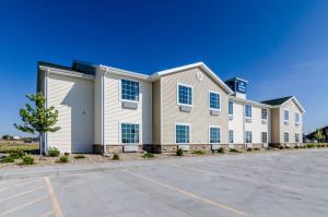 un grand bâtiment blanc avec un parking dans l'établissement Cobblestone Inn & Suites Cambridge, à Cambridge