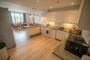 a kitchen with white cabinets and a wooden floor at The Haven Keswick - Spacious Central Apartment in Keswick