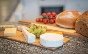 a cutting board with different types of cheese and bread at The Haven Keswick - Spacious Central Apartment in Keswick