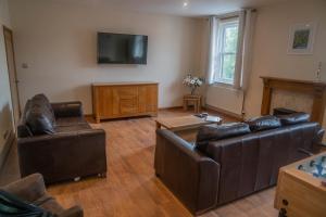 a living room with leather furniture and a flat screen tv at The Haven Keswick - Spacious Central Apartment in Keswick