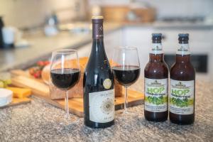 two bottles and two glasses of wine on a counter at The Haven Keswick - Spacious Central Apartment in Keswick