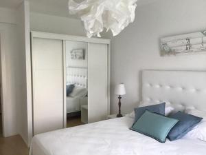 - une chambre avec un lit blanc et un grand miroir dans l'établissement Alvor tendance, à Alvor