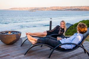 Mossel Bay的住宿－非洲海洋莊園酒店，坐在水边椅子上的男人和女人
