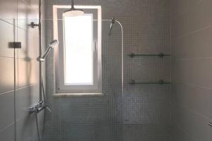 ein Bad mit einer Dusche, einem Fenster und einer Glastür in der Unterkunft Cosy holiday apartment in Lagos in Lagos