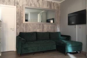 ein grünes Sofa im Wohnzimmer mit Spiegel in der Unterkunft Cosy holiday apartment in Lagos in Lagos