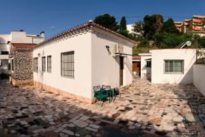 Las Casitas في توريمولينوس: منزل أبيض مع طاولة خضراء وكراسي على الرصيف