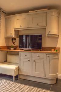 a kitchen with white cabinets and a flat screen tv at Reayrt Ny Marrey in Kirkmichael