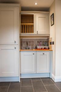 a kitchen with white cabinets and a sink at Reayrt Ny Marrey in Kirkmichael