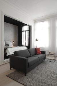 a living room with a couch in front of a bed at Maison Nationale City Flats & Suites in Antwerp