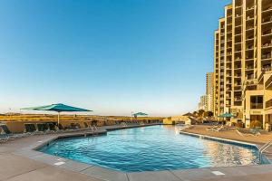 una piscina con sillas y sombrillas junto a los edificios en Phoenix VII, en Orange Beach